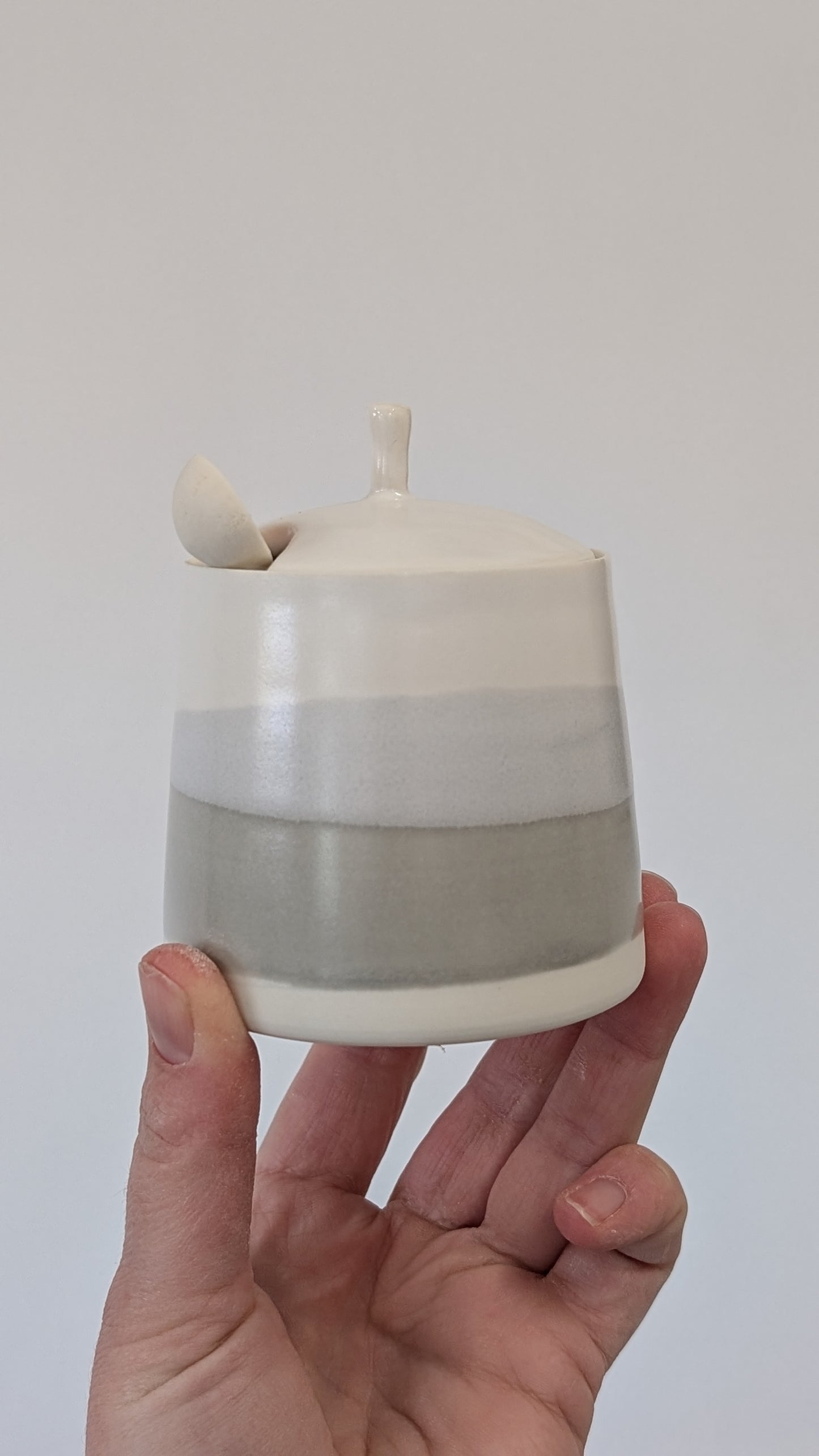 Grey and white wash lidded pot with porcelain spoon.