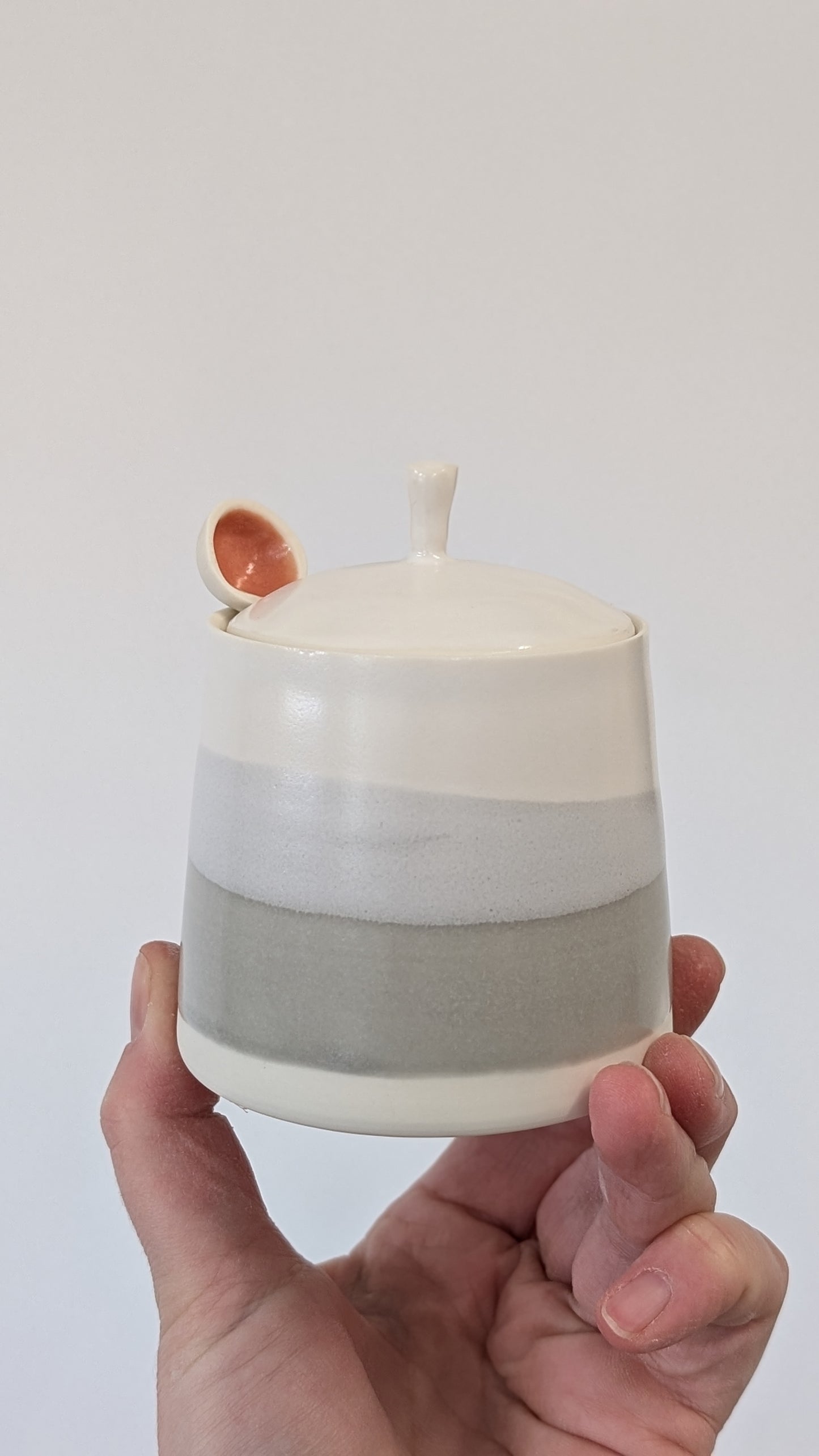 Grey and white wash lidded pot with porcelain spoon.